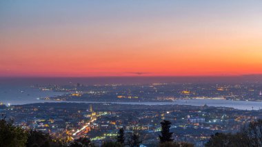 Istanbul night skyline scenery day to night transition timelapse, aerial view over Bosporus channel from Camlica hill. Blue water of Bosporus channel with ship. Traffic on roads