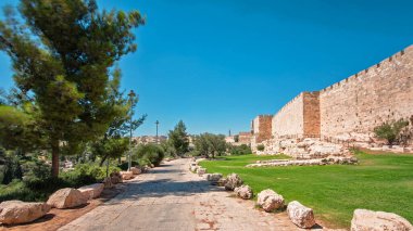 Antik kutsal Kudüs zaman tünelinin savunma duvarı. Parlak güneş tarafından aydınlatılan hiperhız. Yürüyüş yolu ve mavi gökyüzü yakınında harika yeşil çimenler.