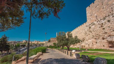 Antik kutsal Kudüs zaman tünelinin savunma duvarı. Parlak güneş tarafından aydınlatılan hiperhız. Harika yeşil çimenler ve mavi gökyüzü. Yolda trafik vardı.