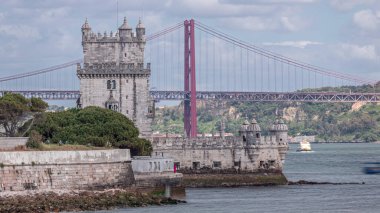 Torre de Belem ya da Belem Kulesi ve Tagus nehri üzerinde kırmızı sembolik 25 de Abril Köprüsü olan şehir manzarası. Lizbon, Portekiz 'de 25 Nisan Köprüsü' nde geçmişi olan Belem 'in Panorama' sı. Bulutlu gökyüzü