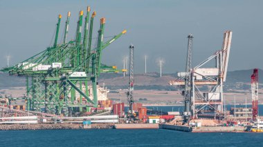 Portekiz, Sines 'deki ticari liman zaman dilimi, iş lojistiği ve ulaşım endüstrisinin konteynır kargo terminalinin hava görüntüsü. Çalışan vinçler ve rüzgar santralleri