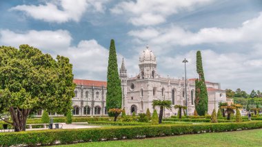 Mosteiro dos Jeronimos ve bahçede çimenliği olan yeşil ağaçlar, Lizbon, Portekiz 'in Belem bölgesinin zaman diliminde yer almaktadır. Manueline tarzı (Portekizce geç Gotik). Mavi gökyüzünde bulutlar