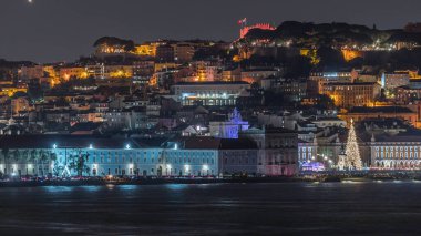 Lizbon Ticaret Meydanı 'nın Noel zamanı aydınlandı. Turistler, açılış ışık gösterisi sırasında parlayan ağacın ve dekorasyonların etrafında toplanıyorlar. Portekiz 'in başkentinde gece sahnesi