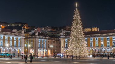 Lizbon 'daki ticaret meydanı, Noel' in aşırı hızıyla aydınlandı. Yükselen bir ağaç ve geceleri kutlayan kalabalıkla. Bir tepenin üzerindeki şenlikli atmosfer dekorasyonları ve tarihi mimarinin zamanı.