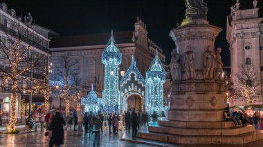 Lizbon, Portekiz 'deki Luis de Camoes meydanında aydınlatılmış şatoyla Noel süslemelerinin gece süreleri. İnsanlar festival ışıkları ve tarihi mimari etrafında yürüyorlar..