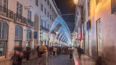 Lizbon şehir merkezindeki Chiado Carmo sokağındaki Noel ışıkları ve dekorasyonları gece aşırı hızlandı. İnsanlar aydınlanmış kemerlerin altında yürürler. Portekiz 'de festival dekorlu tatil atmosferi