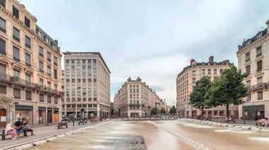 Fransa 'nın Lyon şehrindeki Place de la Republique' in hiperlapesi. Meydanda, tarihi binalarla çevrili büyük bir çeşme var ve insanlar banklarda oturuyor.
