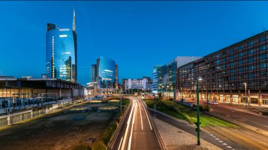 Milano panoramik gökdelenleri, günbatımından sonra, İtalya 'nın Milano şehrinde, Porta Nuova iş bölgesinde günden geceye geçiş. Yollarda trafik vardı. Pencerelerde ışık var. Köprüden üst görünüm