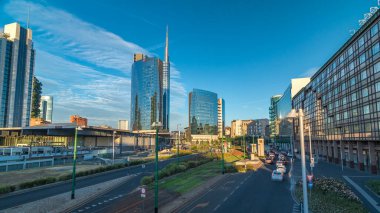 Milan Porta Nuova iş bölgesi timelapse hyperlapse Milan, İtalya, turuncu ışık ile gün batımında içinde modern gökdelenler ile manzarası. Yolda trafik. Köprüsü'nden Üstten Görünüm