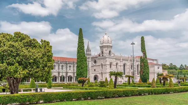 Mosteiro dos Jeronimos ve bahçede çimenliği olan yeşil ağaçlar, Lizbon, Portekiz 'in Belem bölgesinin zaman diliminde yer almaktadır. Manueline tarzı (Portekizce geç Gotik). Mavi gökyüzünde bulutlar