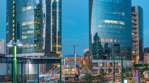 Milan Porta Nuova iş bölgesi gün gece geçiş timelapse Milan, İtalya, güneş battıktan sonra içinde modern gökdelenler ile manzarası. Yolda trafik. Işık içinde pencere eşiği. Köprüsü'nden Üstten Görünüm