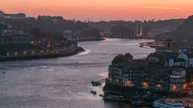 Day to night transition aerial view of the historic city of Porto, Portugal panoramic timelapse from the Dom Luiz bridge. Illuminated waterfront and curved river from above