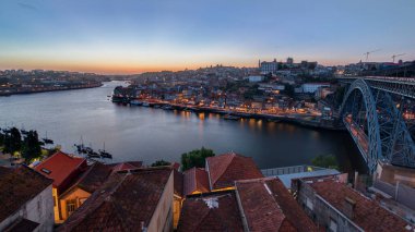 Panorama old city Porto at river Duoro, with Port transporting boats day to night transition timelapse with the Arrabida bridge after sunset, Oporto, Portugal