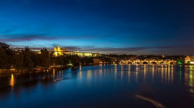 Çek Cumhuriyeti 'nde şatosu olan Prag şehrinin manzarası ve güzel gökyüzü olan Vltava nehrinde gece gündüz bir çok renkli tekne geçiş zamanı. Charles Köprüsü arka planda