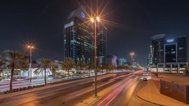 Suudi Arabistan, Riyad 'ın şehir manzarası gece zaman çizelgesi. Işıklı kulelerin, gökdelenlerin, King Fahd Yolu 'nun ve yoğun trafiğin panoramik görüntüsü. Palmiyeler ve sokak lambaları şehrin içinden geçen ana otoyolda.