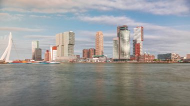 Panorama, Nieuwe Maas River bankasından Wilhelminapier ve Kop van Zuid 'e kadar olan zaman çizelgesini gösteriyor. Modern gökdelenler, gemi terminali ve Erasmus Köprüsü, kıyıdan geçen tekneler.