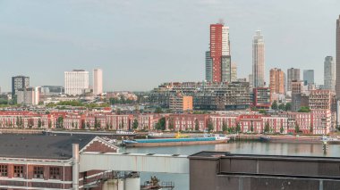 Rotterdam, Hollanda 'daki Katendrecht Yarımadası ve Maashaven Limanı' nın panoramik zaman çizelgesi. Sabah şehir silueti, modern gökdelenler ve Hollanda kıyısı evleri olan eski fabrikalar.
