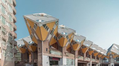 Rotterdam 'daki Küp Evi' nin (Kubuswoningen) hiperlapesi. Eşsiz sarı küp şekilli evler şehrin zaman dilimi içinde yenilikçi mimari sergiliyor. Mavi gökyüzü ve şehir canlılığı. Hollanda