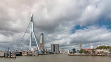 Rotterdam, Hollanda 'daki Maas Nehri' ni kapsayan Erasmus Köprüsü zaman atlaması. Hollanda 'nın en büyük kablo destekli baskülü köprüsü gökdelenleri, rıhtımdaki tekneleri ve dramatik bulutlu gökyüzü arkaplanı