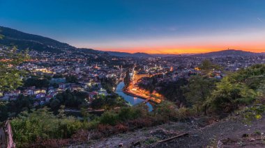 Saraybosna 'nın şehir manzarası, Saraybosna' nın en popüler panoramik noktasından gece geçiş dönemine kadar olan nehir manzarası. Sarı Kale (Zuta Tabija) yakınlarındaki yol, Vratnik
