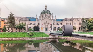 Saraybosna 'daki Güzel Sanatlar Akademisi ve Festina Lente köprüsü, Bosna-Hersek' in zaman atlaması. Bulutlu gökyüzü ve Miljacka nehri yansımaları