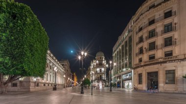 Avenida de la Constitucion gece vakti Seville, İspanya 'da aşırı hız. Iconic Adriatica binası akşam parlıyor. Modern sokak lambaları, yayalar ve şehir atmosferine sahip tarihi mimari