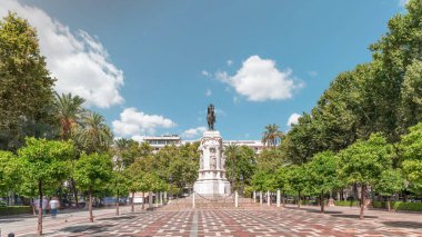 Seville 'deki Plaza Nueva' da, yeşil ağaçlar ve tarihi binalarla çevrili Kral San Fernando 'nun binicilik heykeli yer alıyor. Mavi gökyüzünün altında manzaralı bir şehir alanı