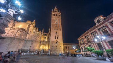 La Giralda ve Seville Katedrali geceleri aşırı hızlanarak altın ışıklarla parıldıyor. Tarihi çan kulesi, gotik detaylar ve aydınlatılmış sokaklar Sevilla, İspanya 'da büyülü bir atmosfer yaratıyor.