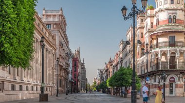 Avda boyunca yürüyen yayalar. De la Constitucion, Seville, İspanya 'nın Casco Antiguo bölgesindeki ana cadde. Edificio de la Adriatica yakınlarındaki zaman dilimi, tarihi binalar ve geçen tramvaylar