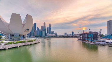 Futuristic architecture flower shape design of the Art Science museum at the foreground timelapse at sunset. Skyscrapers skyline city of Singapore. clipart