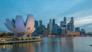 Futuristic architecture flower shape design of the Art Science museum day to night transition timelapse after sunset. Skyscrapers skyline city of Singapore.