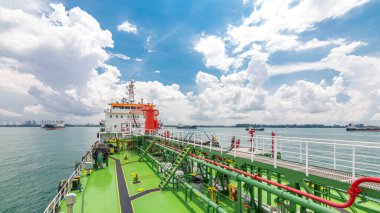 Bulutlu gökyüzünün altındaki tankerin yeşil güvertesi. Üzerinde boru olan vinç operatörle hareket ediyor. Panoramik görünüm