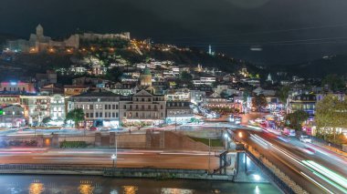 Georgia 'nın Tiflis şehrinde ahşap oymalı balkonları olan renkli geleneksel evler. Aydınlatılmış binalar ve trafik
