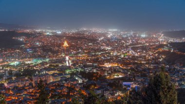 Alacakaranlıkta Tiflis şehri, Gürcistan 'dan gece geçiş zamanı. Şehir merkezinin ve Tiflis 'teki Kura Nehri' nin üst manzarası. Gün batımından sonra Gürcistan başkentinin havadan görünüşü