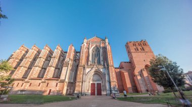 Toulouse 'daki Saint Etienne Katedrali zaman aşımına uğradı. Kilisenin kuzey cephesinin detayları. Gün batımı gölgeleri duvarlarını kaplıyor, önünde yeşil bir park ve yukarıda mavi bir gökyüzü var. Fransa.