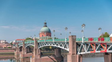 Garonne Nehri 'nin üzerindeki Saint Pierre Köprüsü' nde su ve La Grave Hastanesi 'nin arka planında bulutlu mavi bir gökyüzünün altında yansımaları var. Klasik sokak lambaları cazibe katar. Toulouse, Fransa