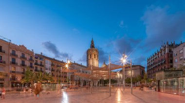 İspanya, Valencia 'daki Plaza de la Reina' da panoramik günden geceye geçiş süreleri aşırı hızlanıyor. Tarihi bir kilise kulesi, hareketli kafeleri ve akşam gökyüzünün altında merkezi bir çeşmesi olan canlı bir meydan..