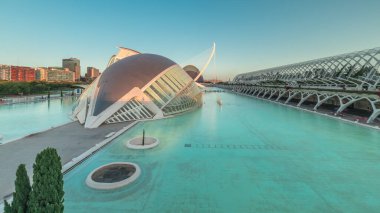 Valencia 'nın Sanat ve Bilim Şehri' nin çarpıcı zamansal hızlandırıcı gölgeleri fütüristik mimari üzerinde hareket ederken sakin suya yansıyor. Günbatımında büyüleyici İspanyol kültürel simgesi