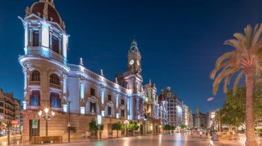 Valencia Belediye Binası (Ajuntament de Valencia) Plaza de Ayuntamiento 'da günden geceye geçiş zamanaşımı üst sürati. Saat kulesi olan tarihi bir bina. İspanya 'nın ana meydanında gezinen insanlar