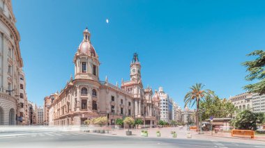 Panorama, Plaza de Ayuntamiento 'da Valencia Belediye Binası' nı (Ajuntament de Valencia) gösteriyor. Mavi gökyüzünün altında saat kulesi olan tarihi bir bina. İspanya 'nın ana meydanında gezinen insanlar