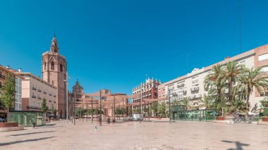 Panorama, İspanya, Valencia 'daki Plaza de la Reina' nın zaman çizelgesini gösteriyor. Tarihi bir kilise kulesi, hareketli kafeler ve sıcak Akdeniz mavi gökyüzünün altında merkezi bir çeşmesi olan canlı bir meydan..