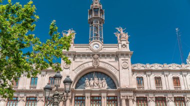 Valensiya 'daki tarihi posta ofisi (Palau de les Comunicacions) Belediye Binası Meydanı' nda (Plaza del Ayuntamiento Meydanı). Süslü cephe, yeşil ağaçlar ve İspanya şehir merkezinde mavi bir gökyüzü..