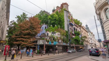 Hundertwasserhaus apartman bloğu zaman atlamalı hiperhıza, dalgalı yüzeylere, toprak ve çimlerle kaplı bir çatıya ve odaların içinden büyüyen büyük ağaçlara sahiptir. Viyana, Avusturya