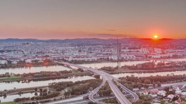 Viyana üzerinde gökdelenler, karayolu kavşağı ve Avusturya 'da nehir kenarındaki gezinti zamanı olan günbatımının hava manzarası. Tuna Kulesi 'nden akşam silueti