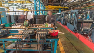 Konveyör montajı, traktörün gövdesini büyük endüstriyel fabrika zaman diliminde sahneleyecek. Kabin montajı, kurulum parçaları özel bir masada.