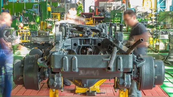 Konveyör montajı, traktörün gövdesini büyük endüstriyel fabrika zaman diliminde sahneleyecek. Çerçeve montajı, Chassis kurulumu ve diğer bölümler etrafındaki işçiler.