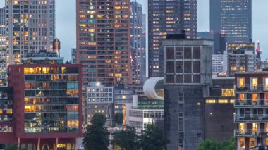 Rotterdam, Hollanda 'daki Katendrecht yarımadası ve Maashaven limanının hava ve gece geçiş zamanı. Günbatımından sonra parlayan pencereleri olan modern gökdelenler.