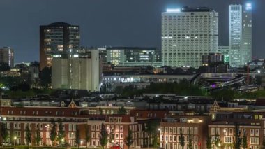 Geceleri Katendrecht yarımadasının panoramik zaman çizelgesi ve Hollanda Rotterdam 'daki Maashaven limanı. Aydınlatılmış şehir silüeti ve modern kuleleri olan geleneksel Hollanda rıhtım evleri