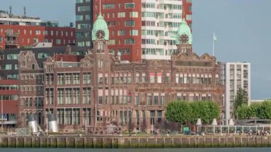 Rotterdam 'daki New York Oteli' nin tarihi görüntüsü. Eski Hollanda-Amerika Hat Karargahı. Tekneler geçerken insanlar rıhtımda dinleniyor. Limanın yanındaki ikonik mimari