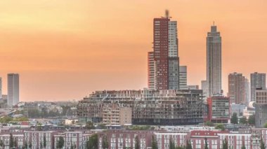 Günbatımında Rotterdam şehir merkezindeki modern binaların hava zaman çizelgesi, Hollanda. Finans bölgesinde kuleler ve gökdelenler, turuncu gökyüzü ile eski fabrika canlı bir ufuk çizgisi oluşturur